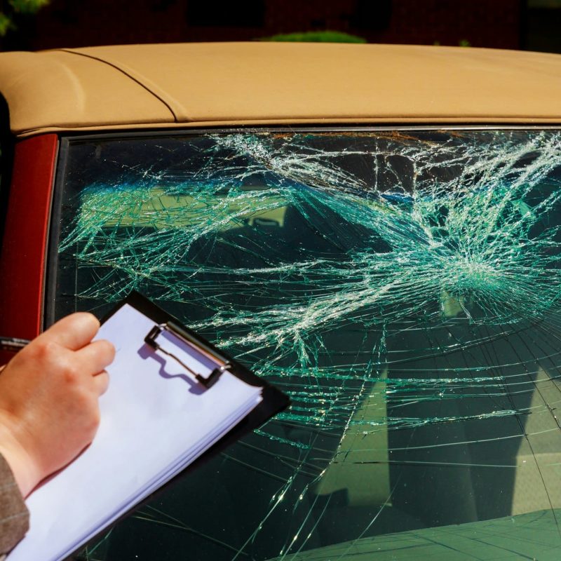 Insurance agent writing report on clipboard after car accident